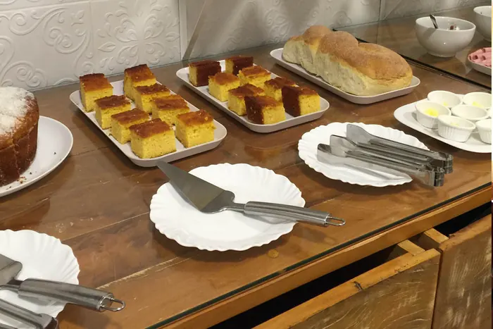 Mesa do café da manhã com bolo de milho, pão caseiro e doces